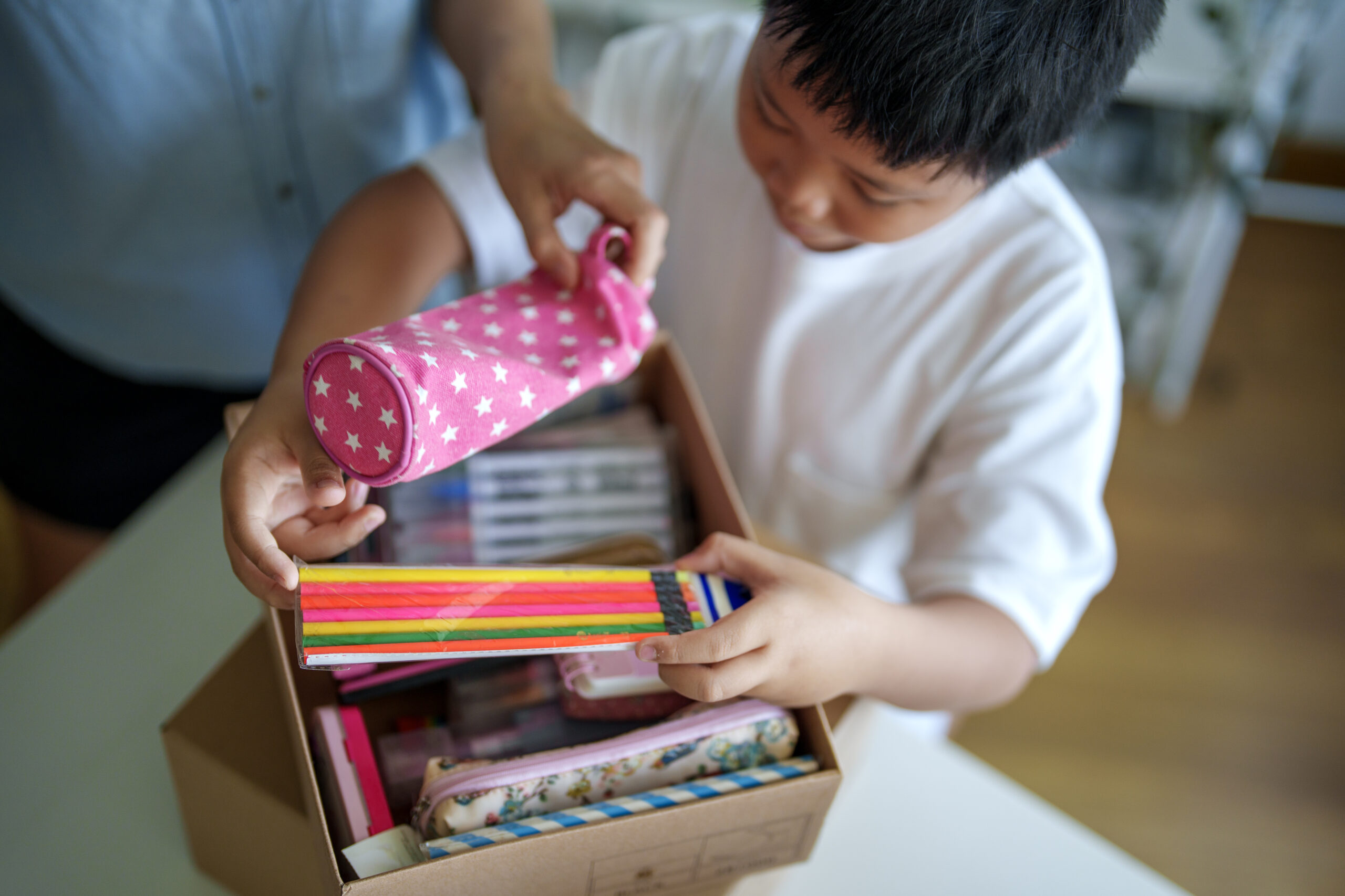 Child placing reusable school supplies into a cardboard box