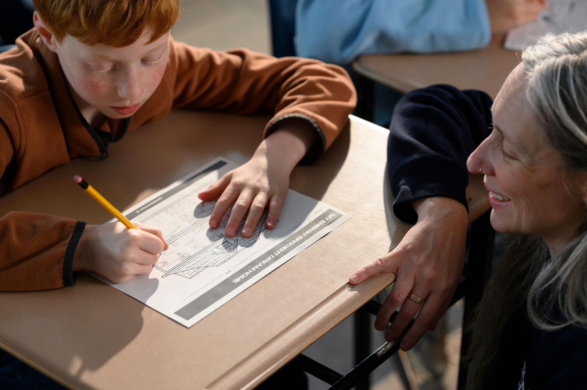 teacher speaking to student at desk